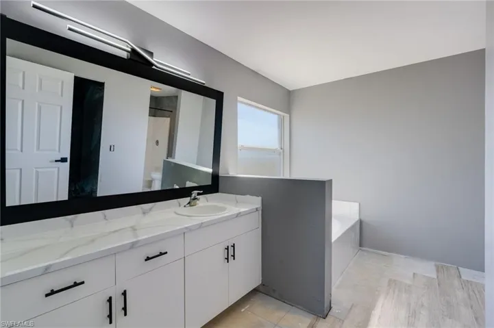 Bathroom with vanity, a garden tub, and a shower with shower door