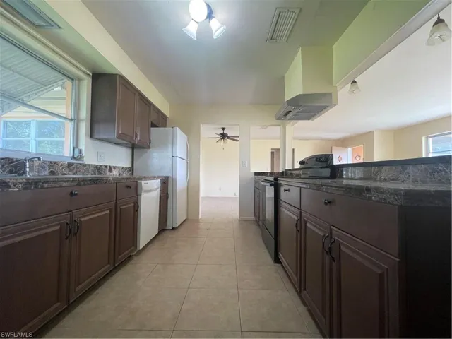 Kitchen with stove, dishwasher, light tile patterned floors, and plenty of natural light
