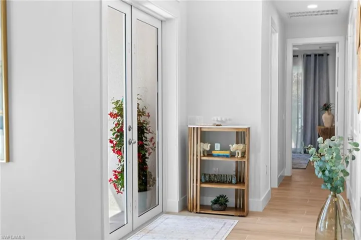 Entryway with French doors featuring textured glass, leading to an outdoor area with vibrant red foliage