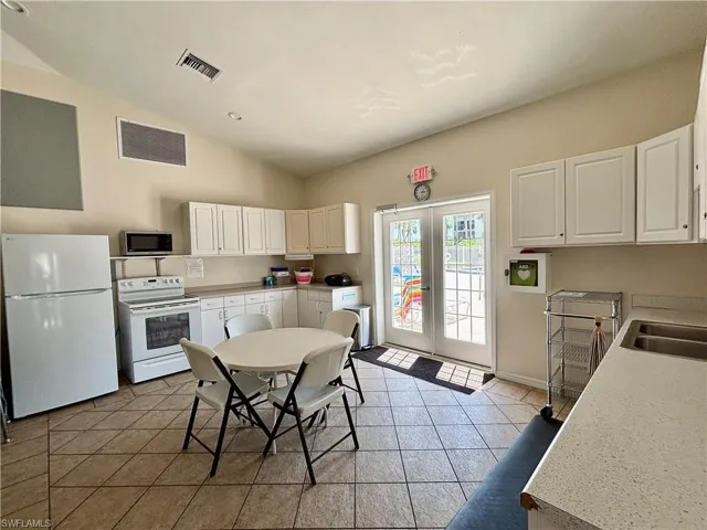 Clubhouse Kitchen with french doors, white appliances, and light tile patterned flooring