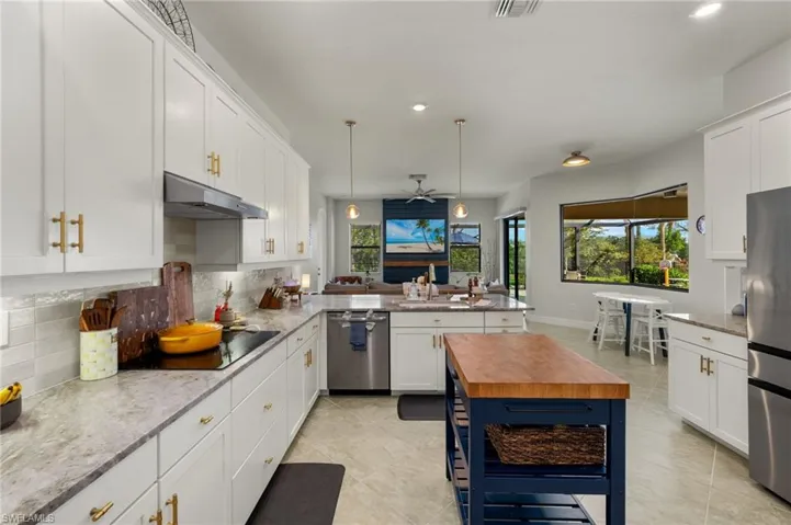 Kitchen with a peninsula, white cabinetry, tasteful backsplash, light stone countertops, and recessed lighting