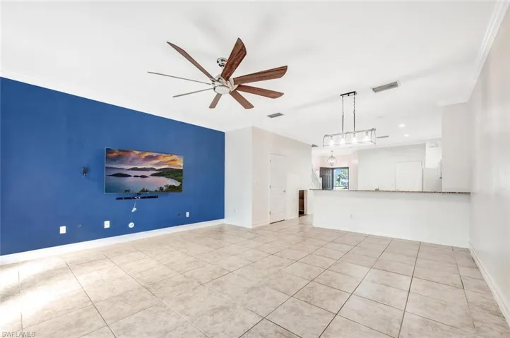 Unfurnished living room featuring light tile patterned flooring, ornamental molding, and ceiling fan
