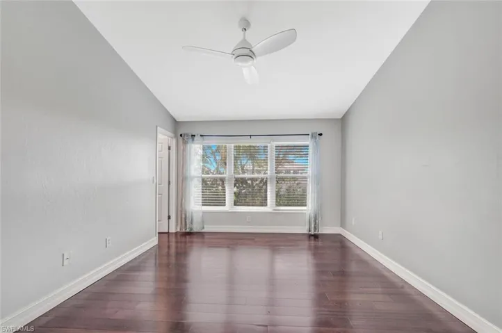 Owners suite with lofted ceiling, ceiling fan, and dark wood-type flooring
