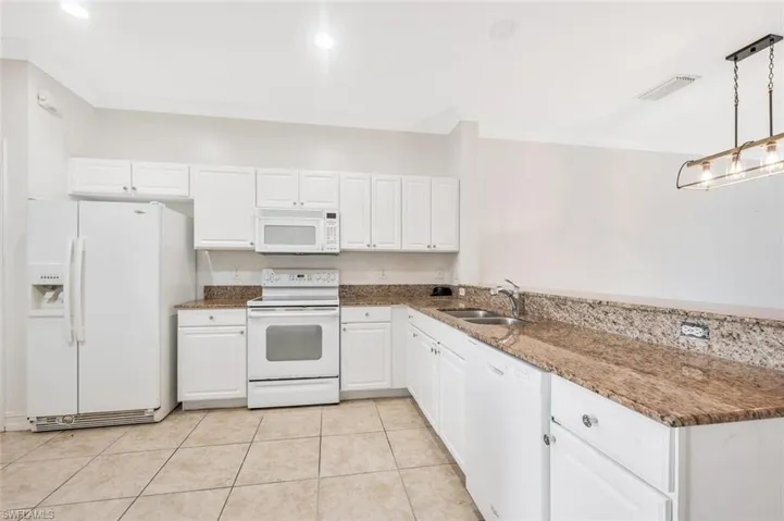 Kitchen featuring white cabinetry, hanging light fixtures, white appliances, crown molding, and stone countertops