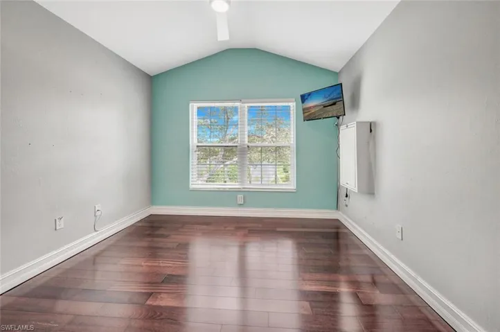 Third bedroom featuring lofted ceiling and dark hardwood / wood-style floors