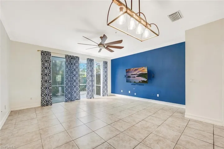 Spare room with crown molding, light tile patterned flooring, and ceiling fan