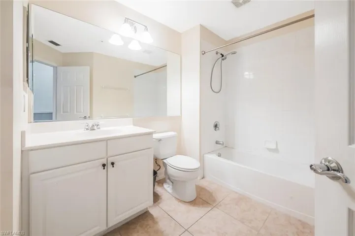 Full bathroom with vanity, tile patterned flooring, tiled shower / bath, and toilet