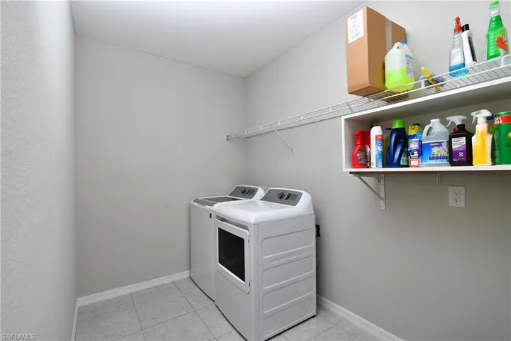 Laundry area featuring light tile patterned floors and washing machine and clothes dryer