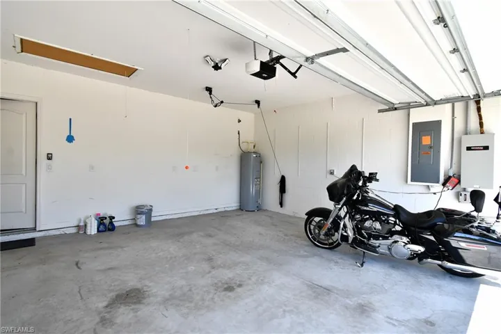 Garage featuring a garage door opener, water heater, and electric panel