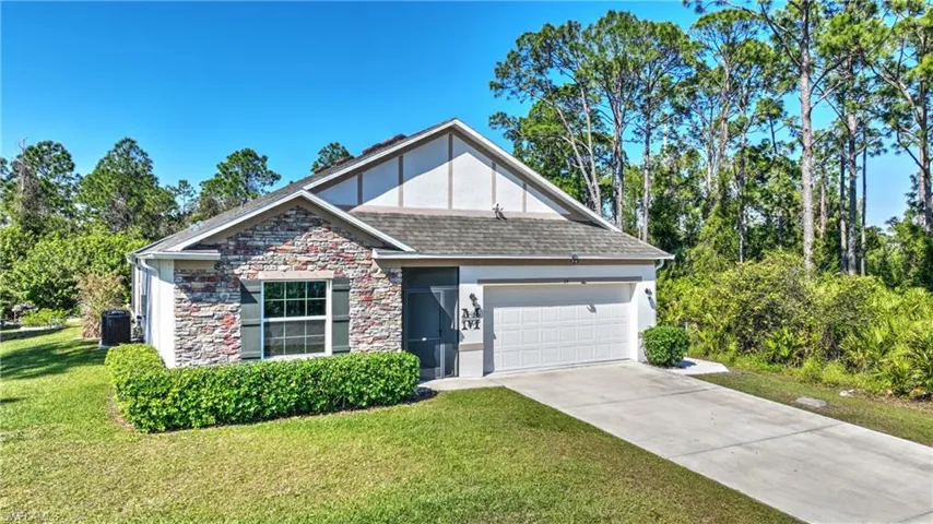 View of front of home featuring a garage, central AC, and a front yard