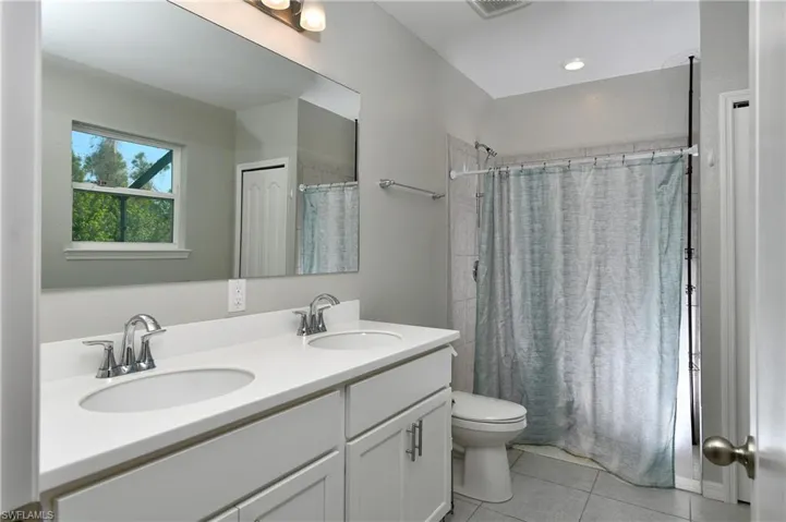 Bathroom featuring vanity, tile patterned flooring, toilet, and curtained shower