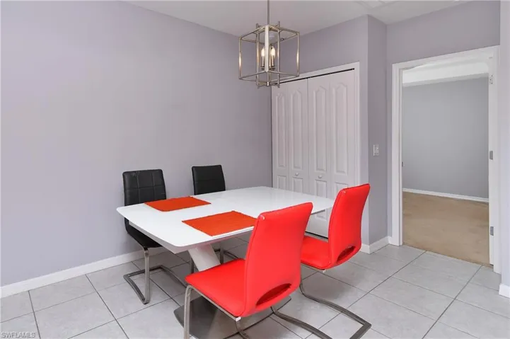 Dining room with light tile patterned flooring and an inviting chandelier