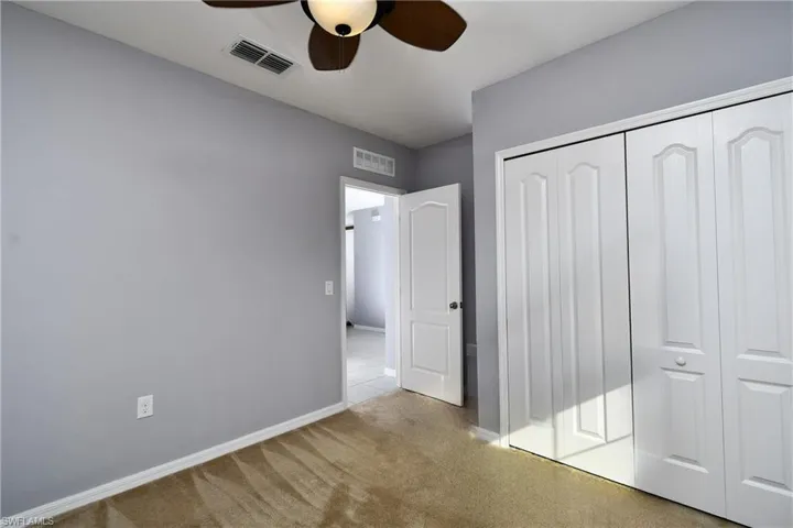 Unfurnished bedroom with ceiling fan, light colored carpet, and a closet