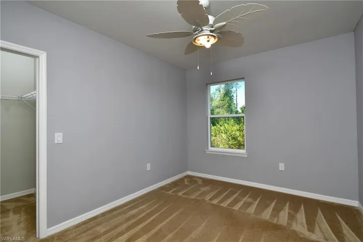 Unfurnished bedroom with carpet, ceiling fan, a walk in closet, and a closet