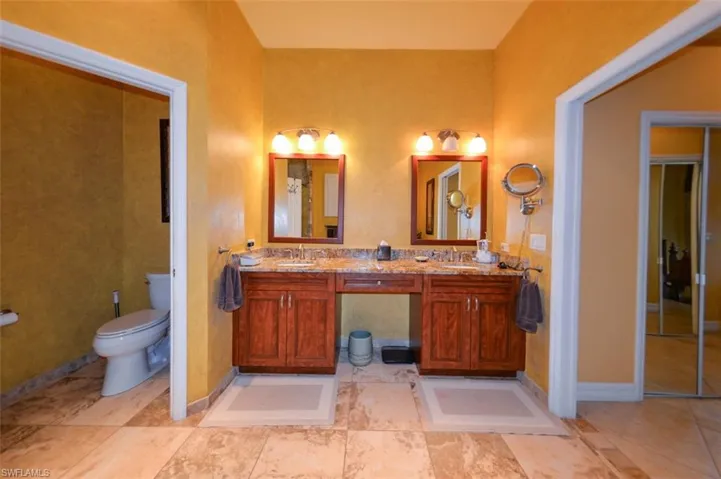 Bathroom featuring double vanity, tile patterned floors, and toilet