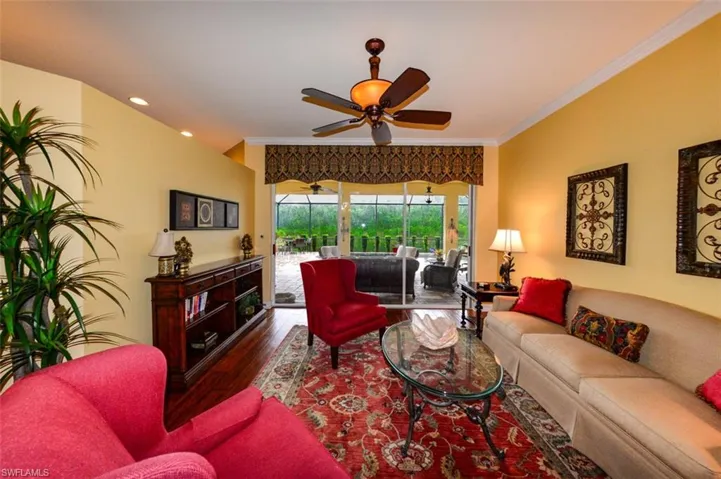 Living room featuring dark wood-type flooring, ornamental molding, and ceiling fan