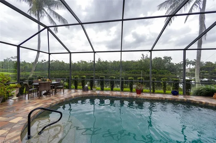 View of pool featuring a patio and glass enclosure