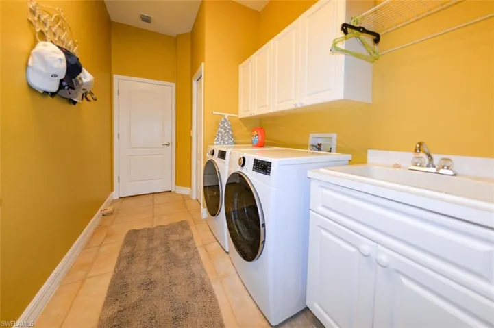 Washroom with sink, washer and dryer, cabinets, and light tile patterned floors