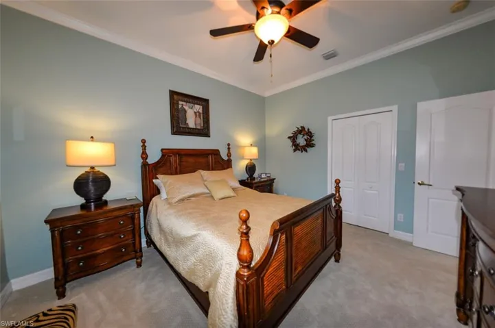Bedroom with a closet, crown molding, ceiling fan, and light colored carpet
