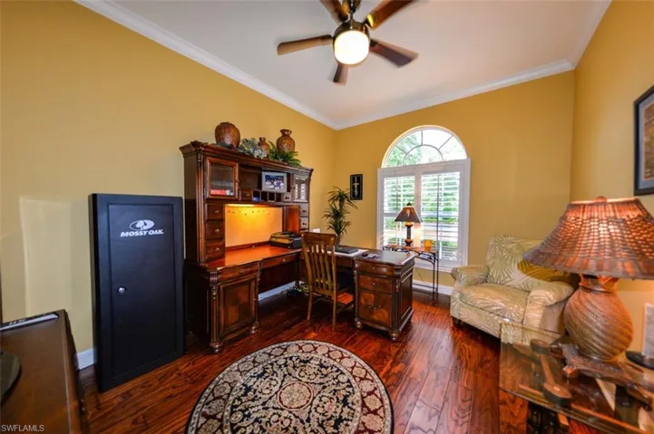 Home office featuring ornamental molding, ceiling fan, and dark wood-type flooring