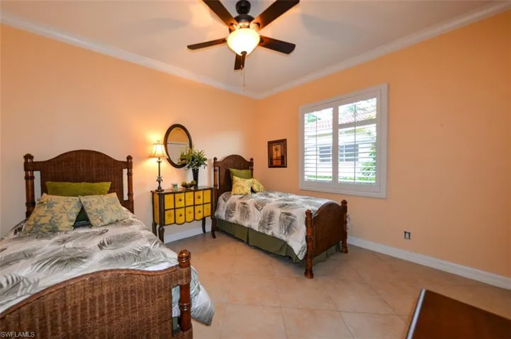 Bedroom with tile patterned floors, ceiling fan, and crown molding
