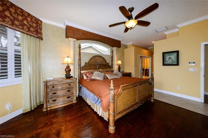 Bedroom with ornamental molding, ornate columns, dark hardwood / wood-style flooring, and ceiling fan