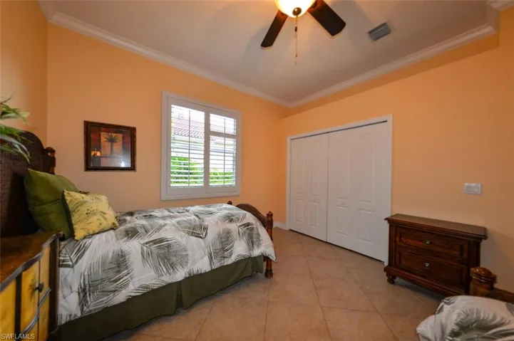 Tiled bedroom featuring a closet, ornamental molding, and ceiling fan