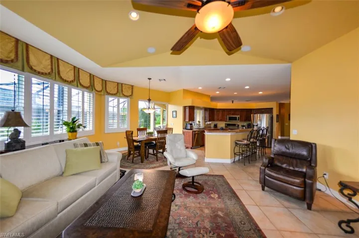 Tiled living room with ceiling fan and vaulted ceiling