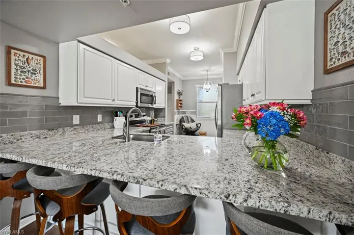 Kitchen with sink, appliances with stainless steel finishes, kitchen peninsula, and backsplash