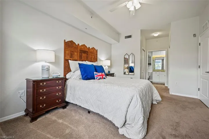 Carpeted bedroom with ensuite bathroom and ceiling fan