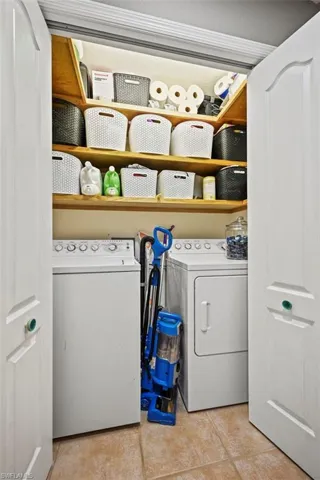 Laundry area with washer and clothes dryer and light tile patterned floors