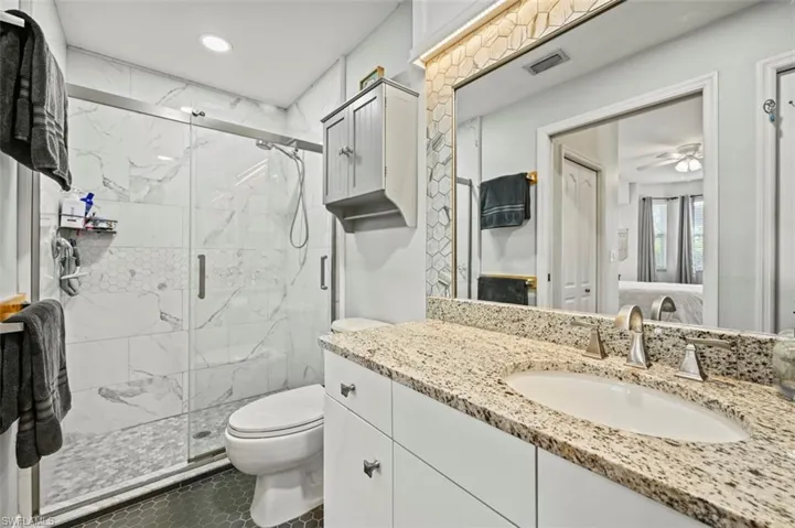 Bathroom with a shower with door, tile patterned floors, toilet, and vanity