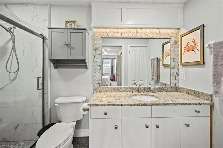 Bathroom featuring vanity, a shower with door, and toilet