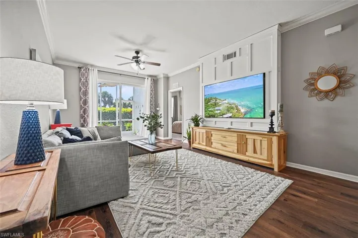 Living room featuring ornamental molding, ceiling fan, and dark hardwood / wood-style floors
