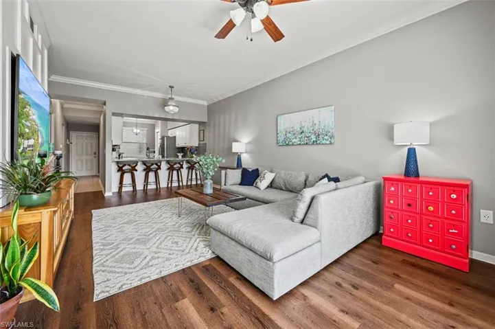 Living room featuring ceiling fan, dark hardwood / wood-style flooring, and ornamental molding
