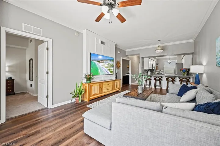 Living room with crown molding, hardwood / wood-style floors, and ceiling fan