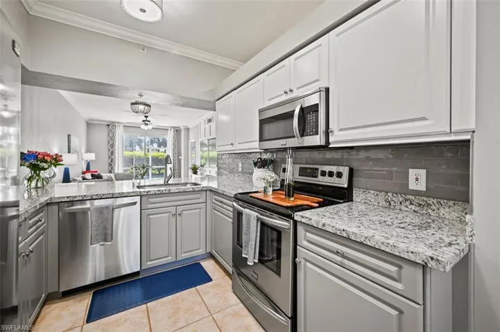 Kitchen featuring light tile patterned flooring, stainless steel appliances, ornamental molding, sink, and backsplash