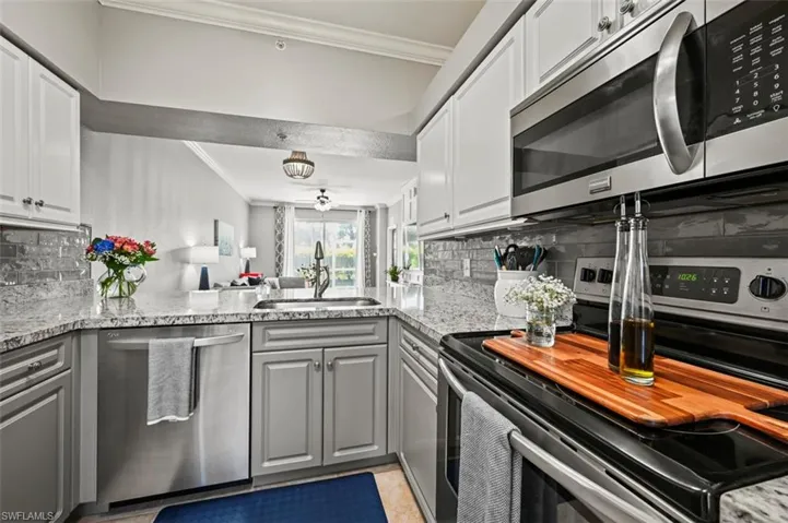 Kitchen featuring decorative backsplash, light stone countertops, kitchen peninsula, and stainless steel appliances