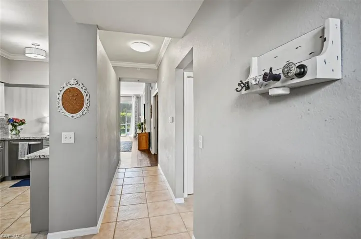Hallway featuring light tile patterned flooring and ornamental molding