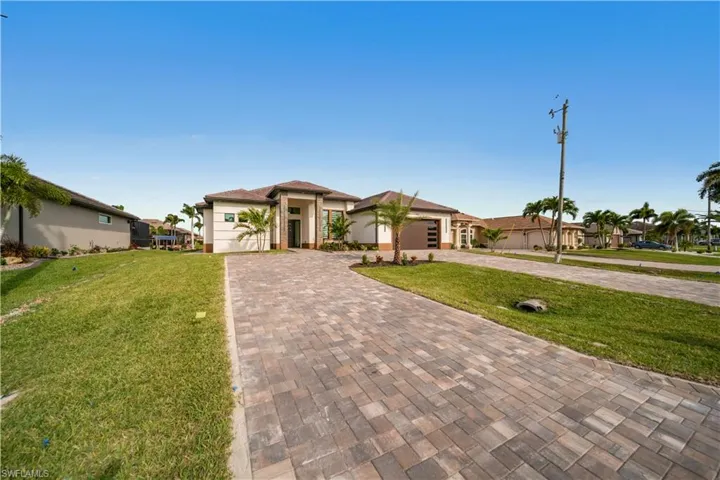View of front of house featuring a front lawn, decorative driveway, a garage, and stucco siding