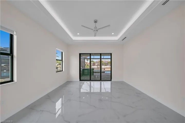 Empty room featuring a tray ceiling, marble finish floor, baseboards, ceiling fan, and recessed lighting