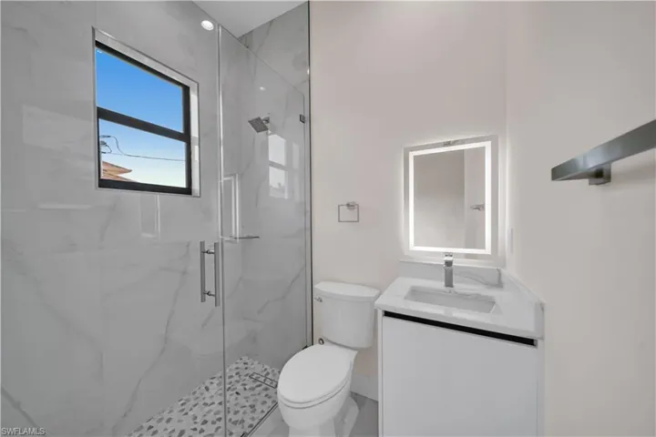 Full bathroom with toilet, vanity, and a marble finish shower