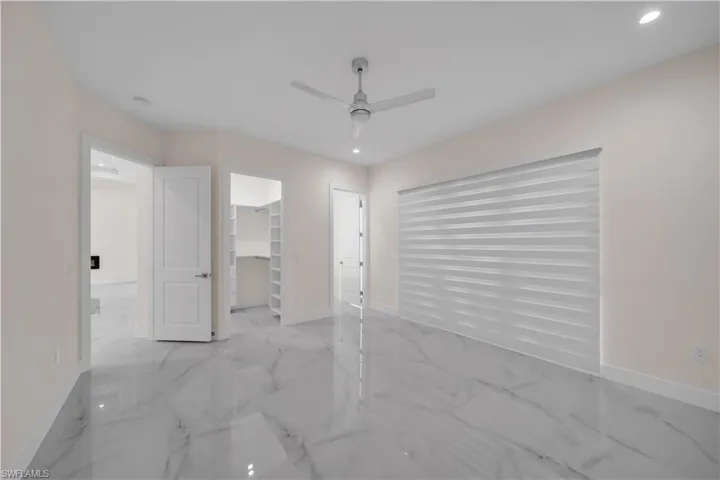 Unfurnished bedroom with baseboards, marble finish floor, recessed lighting, a ceiling fan, and a spacious closet
