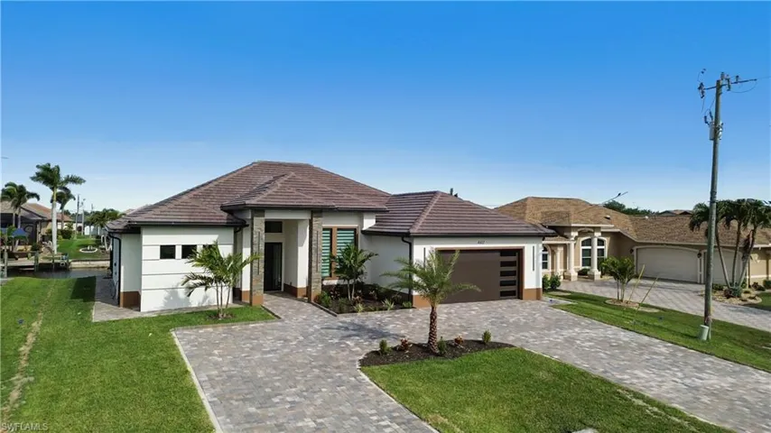 View of front of house featuring a front yard, decorative driveway, stucco siding, and an attached garage