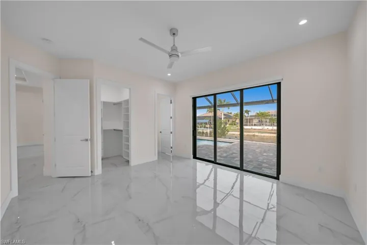 Unfurnished bedroom with baseboards, marble finish floor, access to outside, a ceiling fan, and a spacious closet