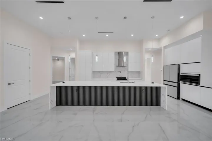 Kitchen with white cabinets, marble finish floor, modern cabinets, and freestanding refrigerator