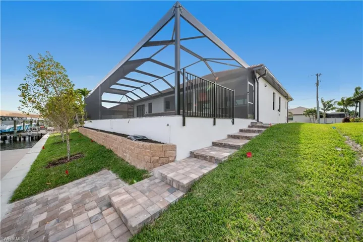 View of property exterior featuring a lawn, a lanai, and stucco siding