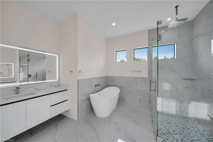 Full bath featuring vanity, a marble finish shower, marble finish floor, a freestanding bath, and recessed lighting