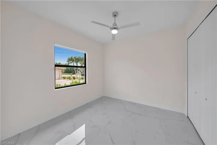 Unfurnished room featuring marble finish floor, baseboards, and ceiling fan