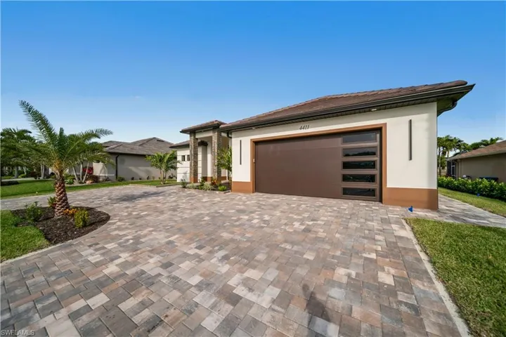 Prairie-style house featuring a garage, decorative driveway, and stucco siding